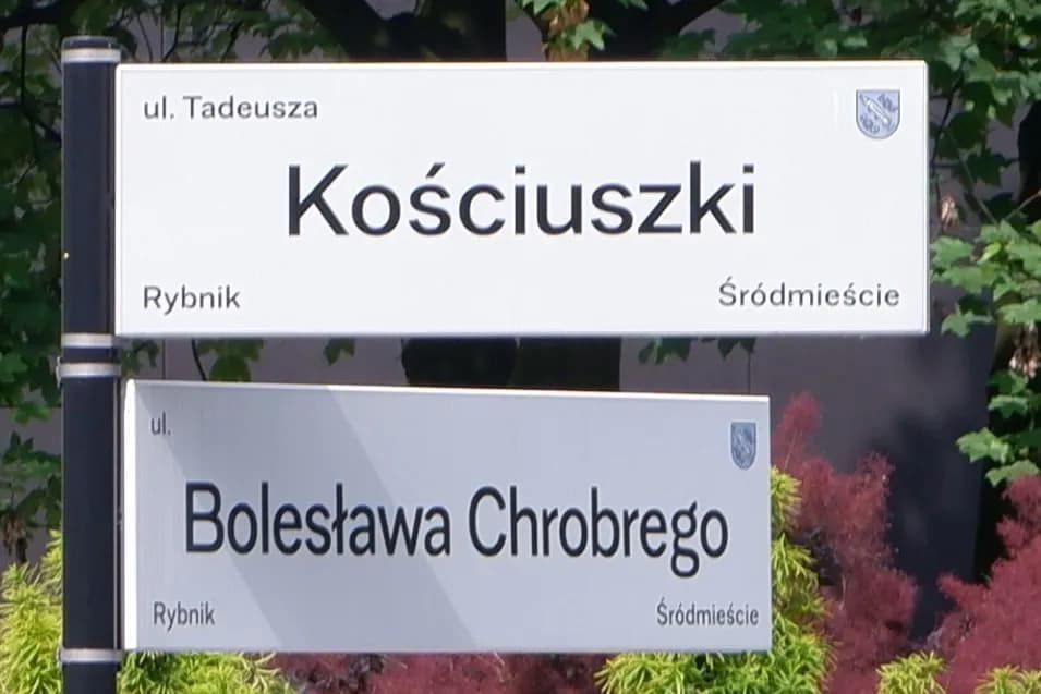 Two street signs mounted on a pole, the top one for "ul. Tadeusza Kościuszki" and the bottom for "ul. Bolesława Chrobrego," both indicating "Rybnik" and "Śródmieście."