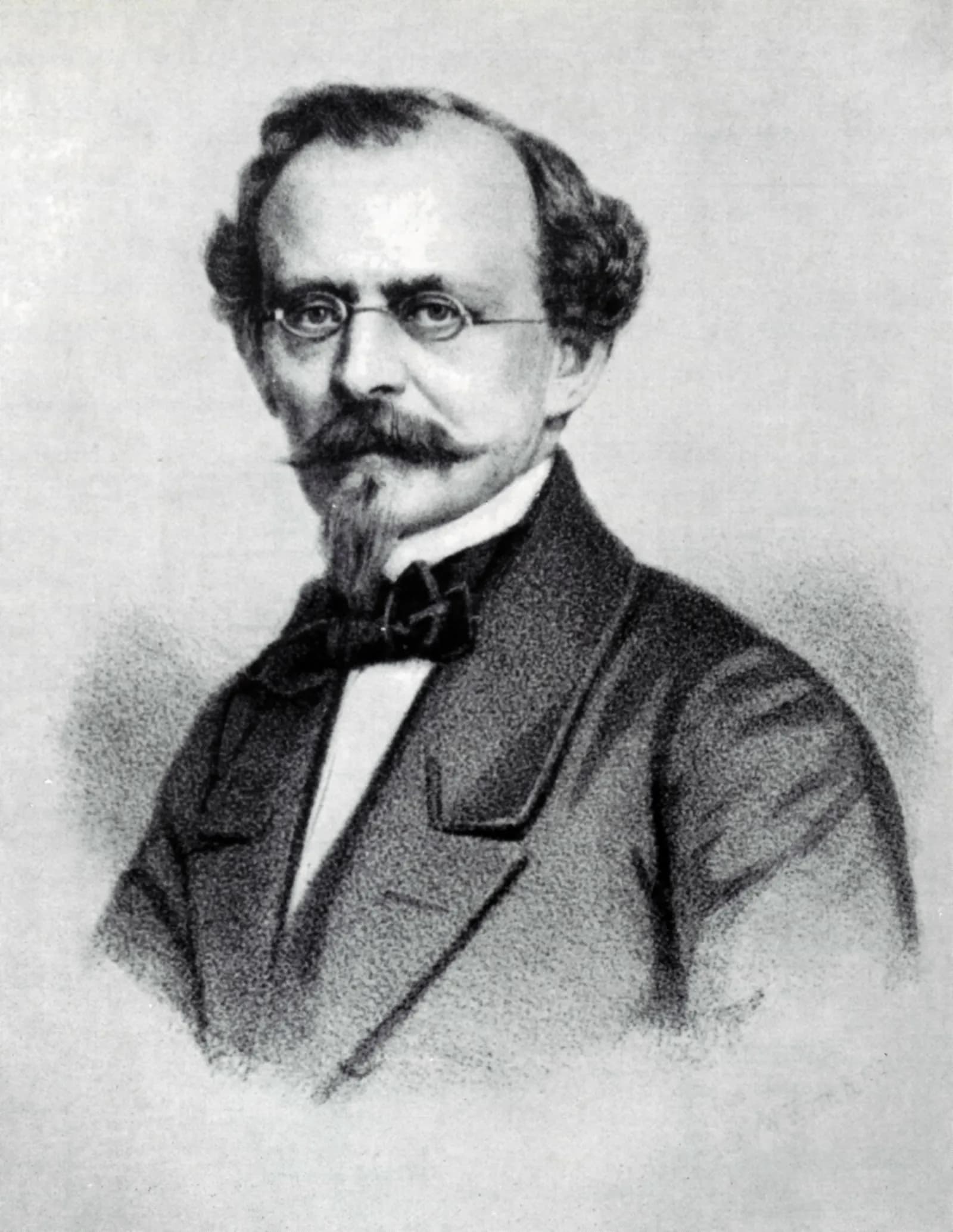 A black and white portrait of a man with glasses, a mustache, and a goatee, wearing a suit and bow tie.